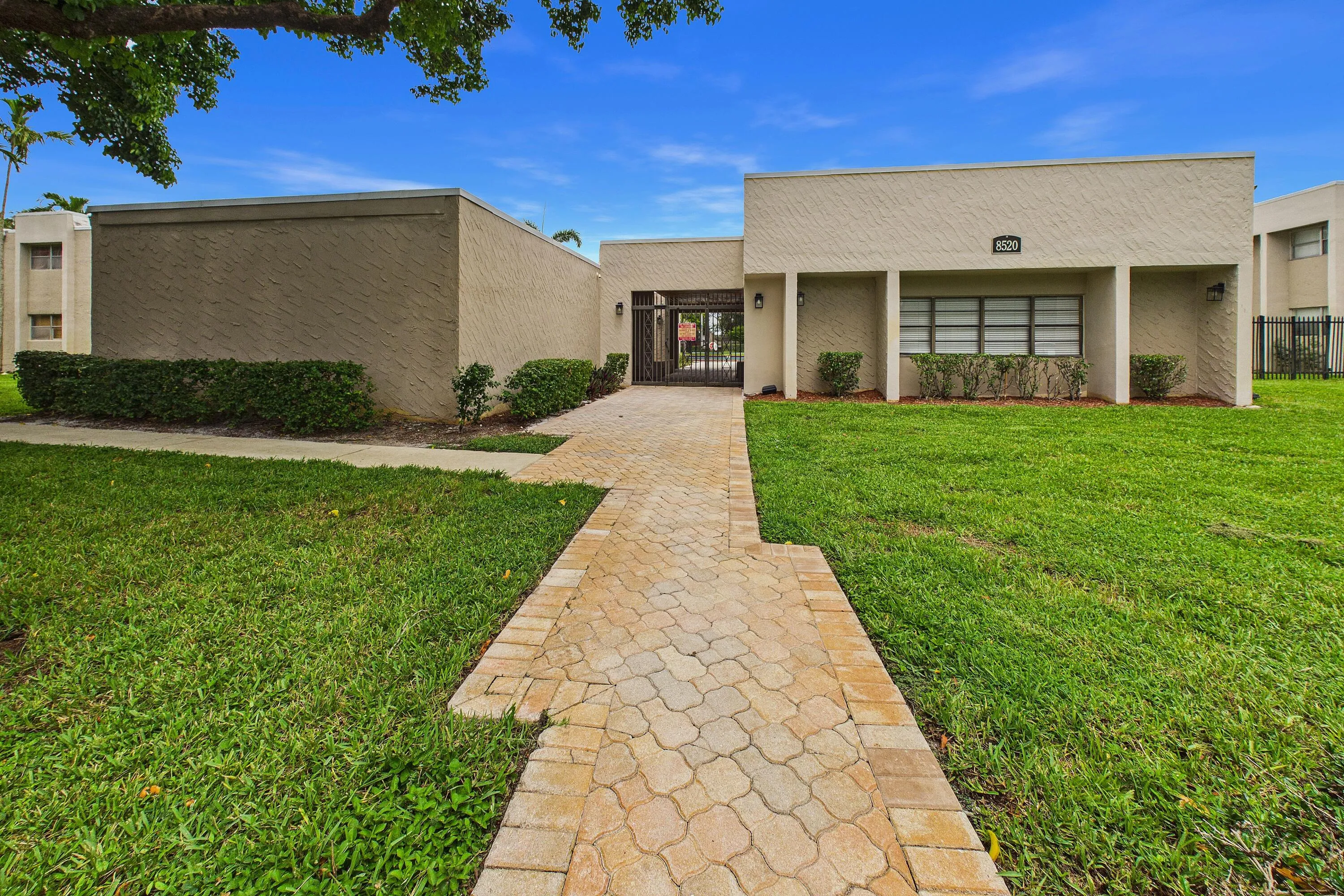 Property exterior featuring a textured facade, a paver pathway, and established landscaping
