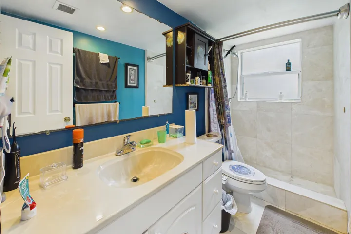 White vanity with integrated sink, chrome faucet, and storage cabinetry