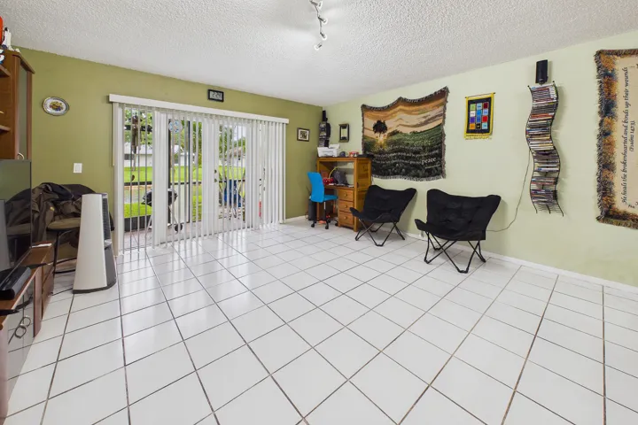 White tile flooring, light green painted walls, and glass sliding doors with vertical blinds