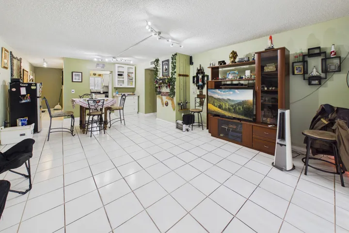 Spacious open-concept living area featuring white square tile flooring
