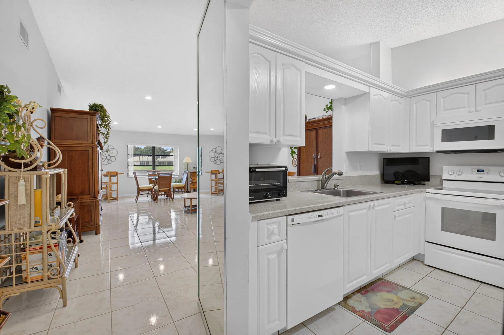 Kitchen featuring white cabinetry, light-toned countertops, a white built-in microwave, and a white electric range