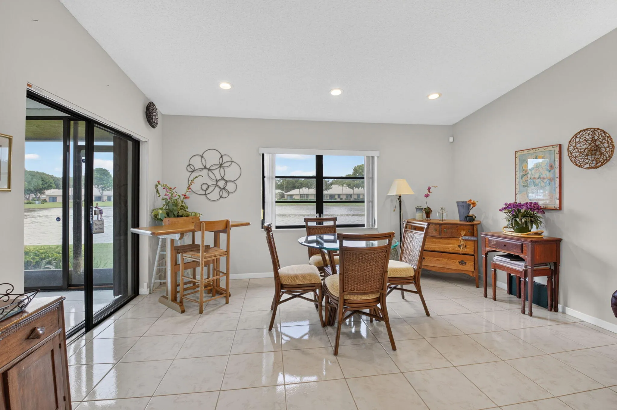 Neutral Tile flooring, recessed ceiling lighting, sliding glass door, and large window with exterior water feature