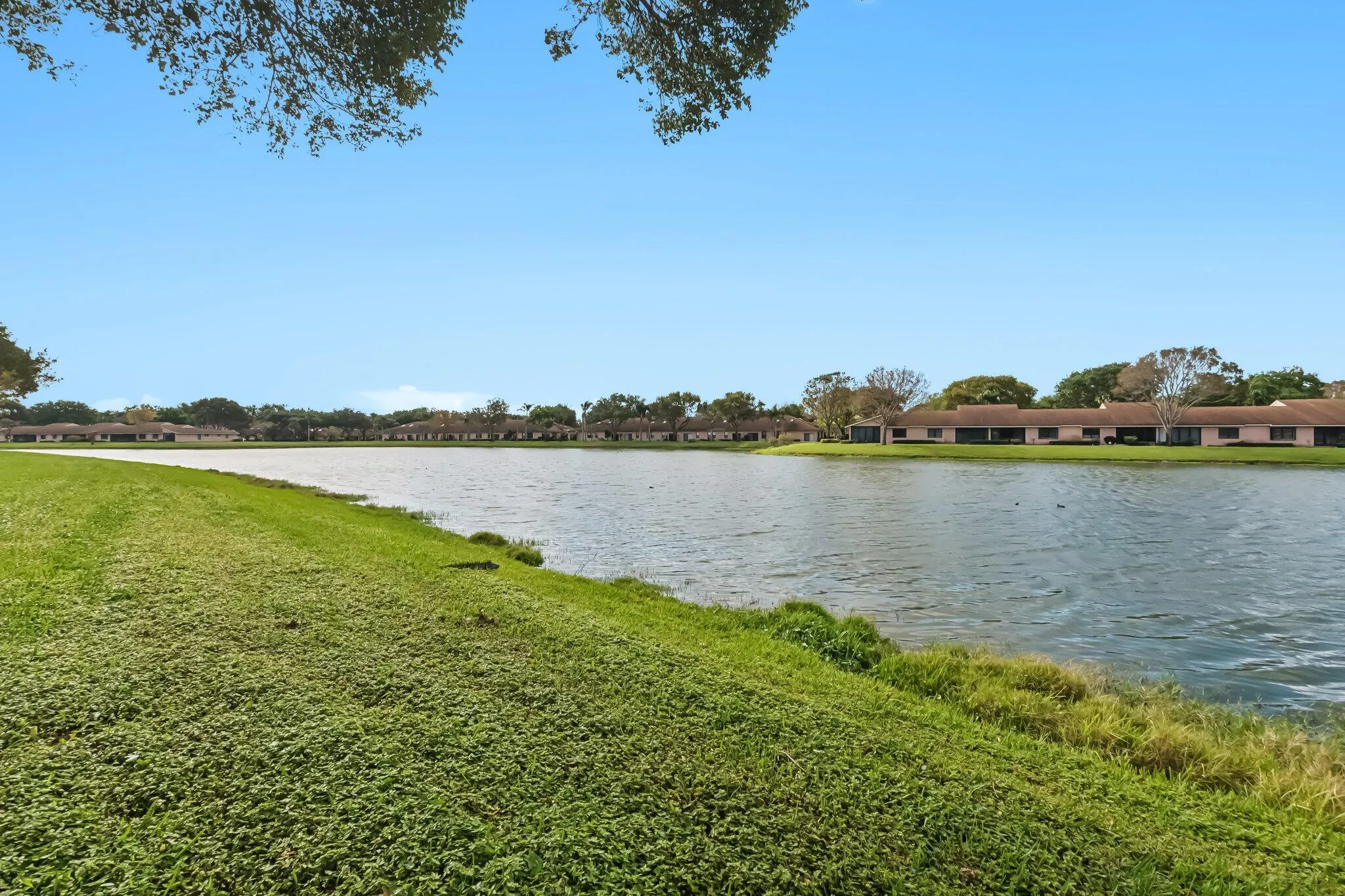 Expansive waterfront property featuring a large lake, surrounding greenery, and a clear sky