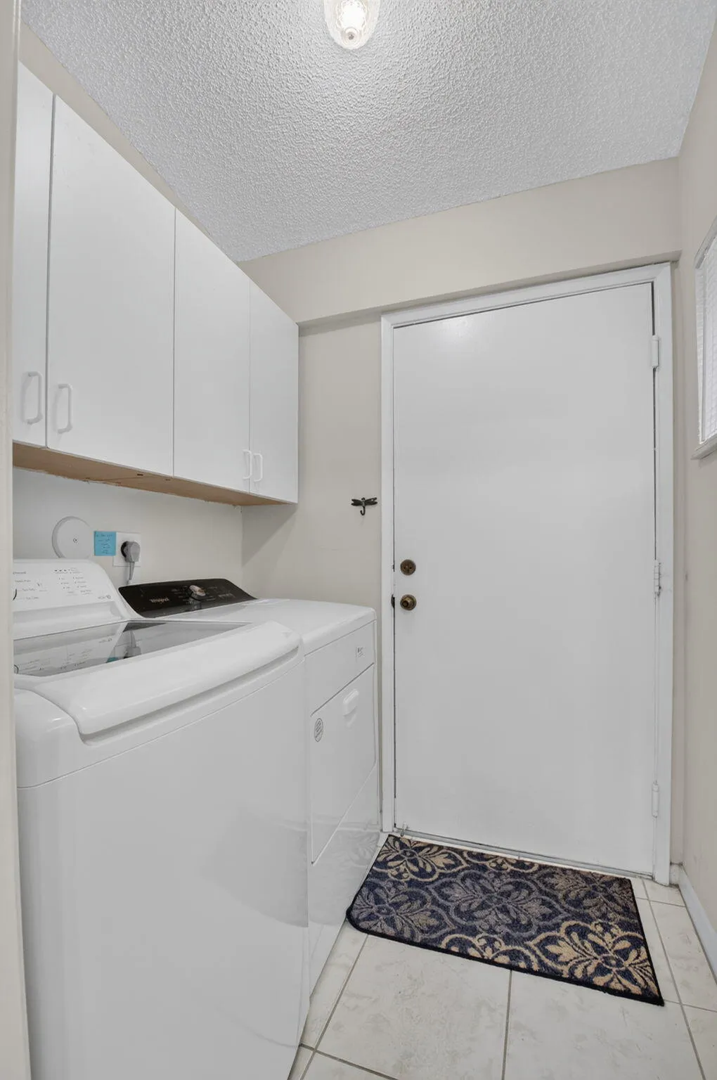 White cabinetry with hardware, light tile flooring, and overhead lighting