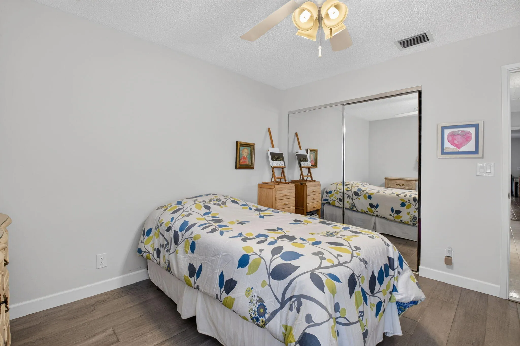 Laminate flooring, ceiling fan with light fixture, and mirrored closet doors