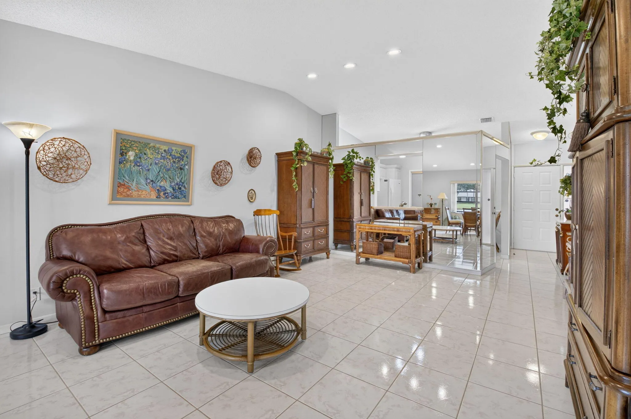 Vaulted ceiling, recessed lighting, tile flooring, mirrored wall accents, and a paneled entry door