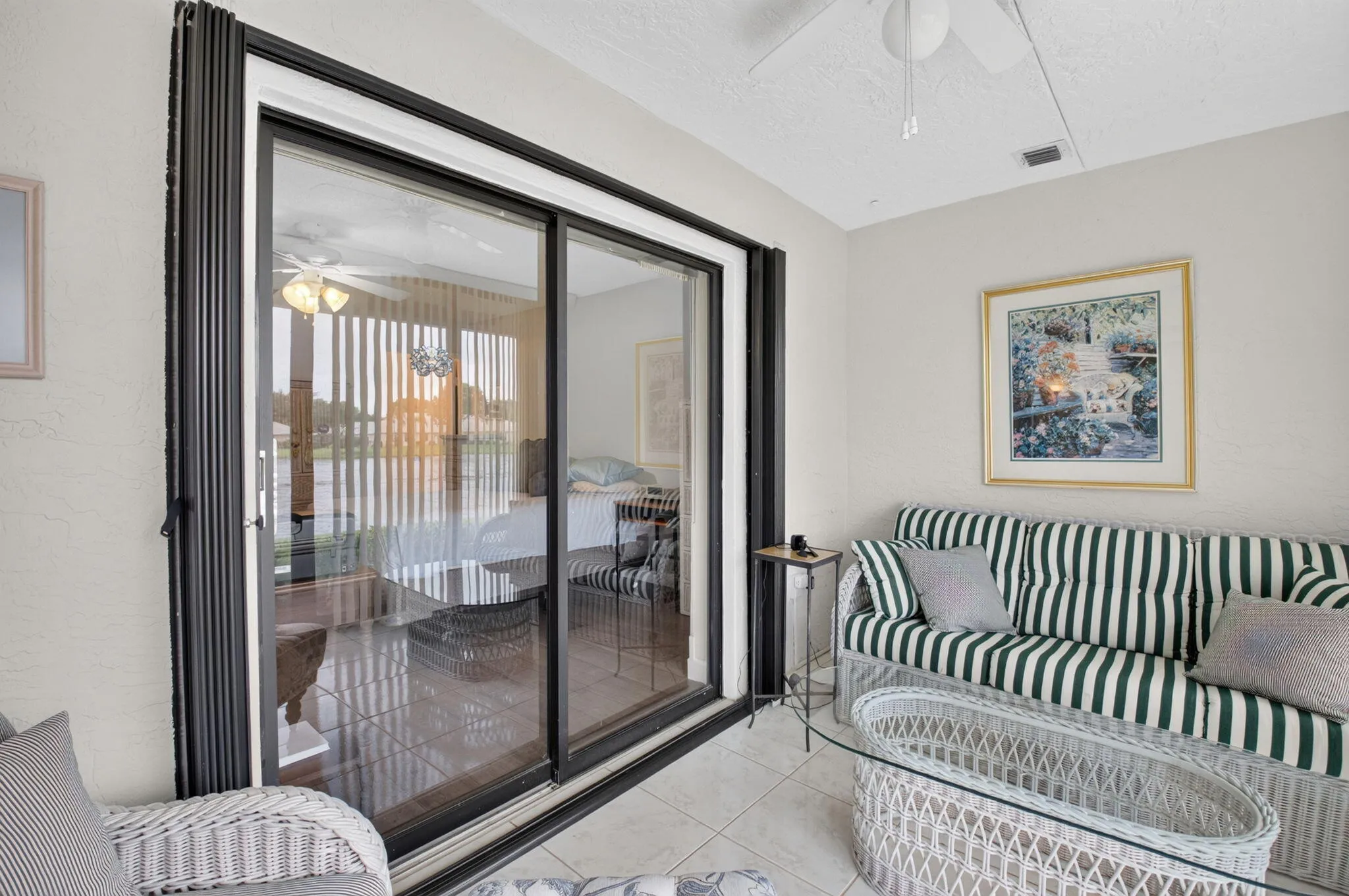 Sliding glass doors, white ceiling fan, tile flooring, and textured walls