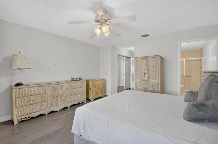 Ceiling fan with integrated lighting, vinyl flooring, white painted walls, and an open doorway to an adjacent space
