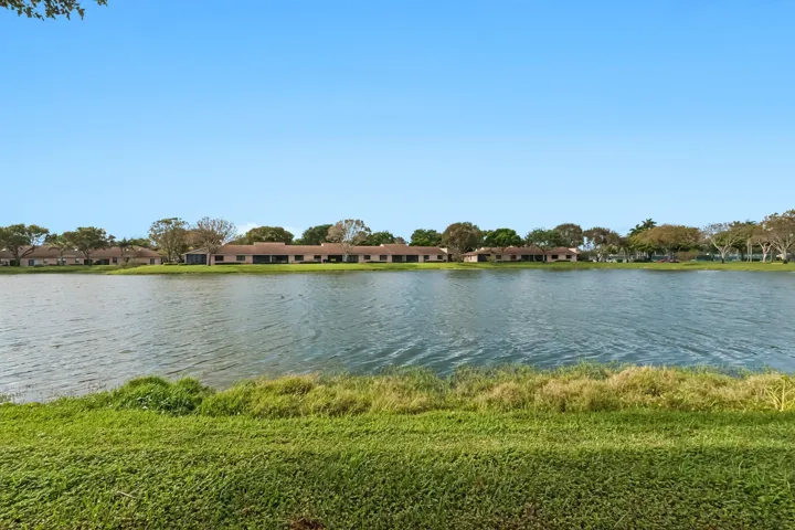 Expansive waterfront property featuring a large lake, surrounding greenery, and a clear sky