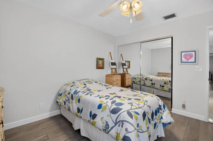 Laminate flooring, ceiling fan with light fixture, and mirrored closet doors