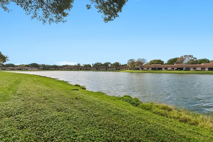 Expansive waterfront property featuring a large lake, surrounding greenery, and a clear sky