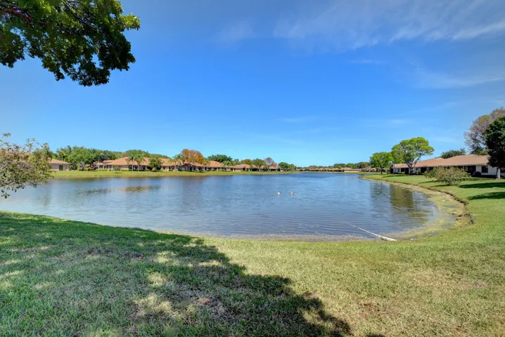 Expansive waterfront property featuring a large lake, surrounding greenery, and a clear sky