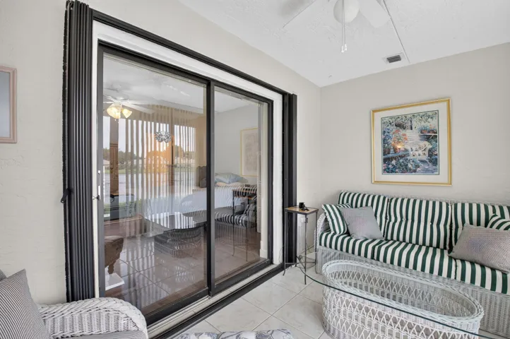 Sliding glass doors, white ceiling fan, tile flooring, and textured walls