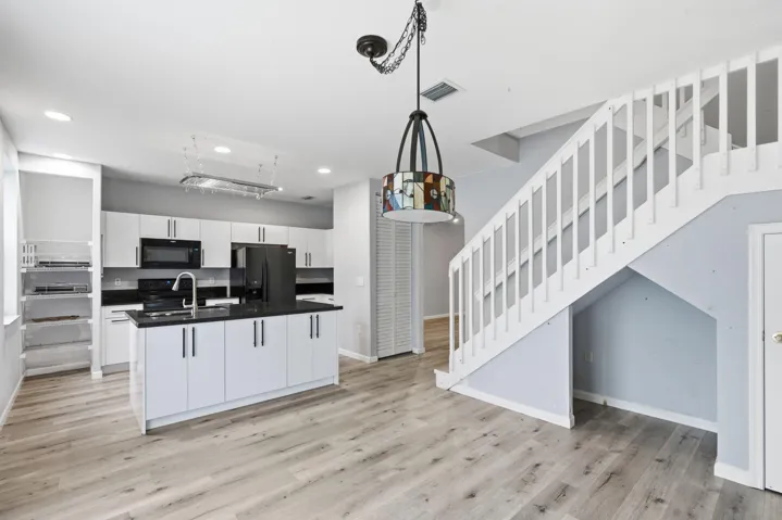 Open-concept kitchen with white cabinetry and dark countertops