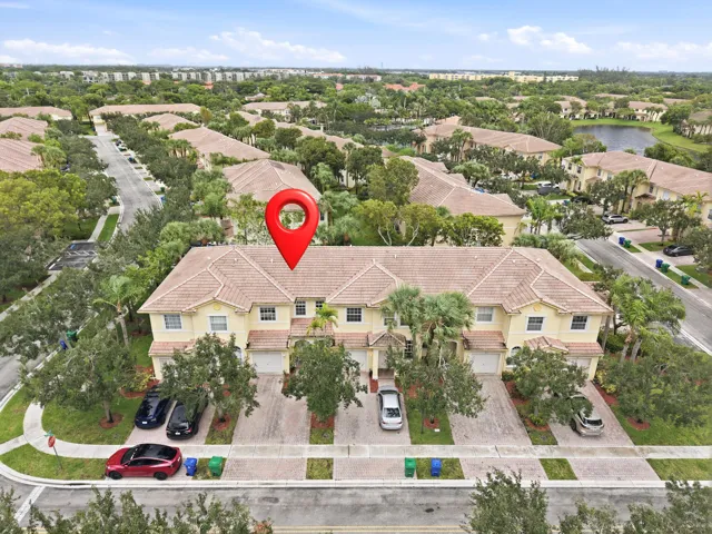 Multi-unit property with a Mediterranean-style roof, light-colored exterior, and individual garage access