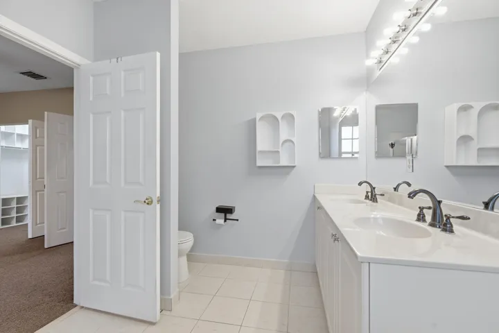 Dual vanity with white cabinetry, integrated sinks, dark bronze faucets, and a full-width mirror