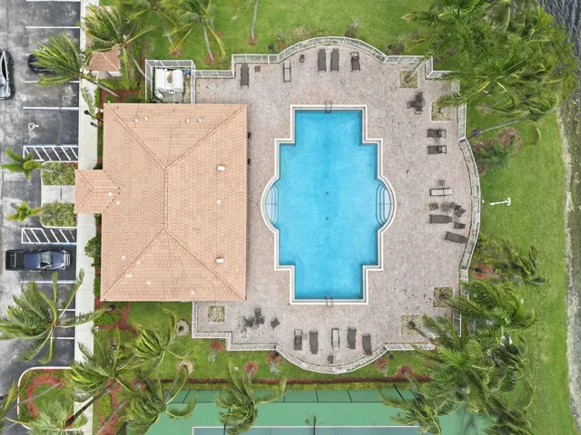 Community pool with an integrated spa, paver deck, and adjacent clubhouse