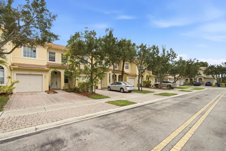 Two-story stucco exterior with a tile roof, an integrated garage, and a paver driveway