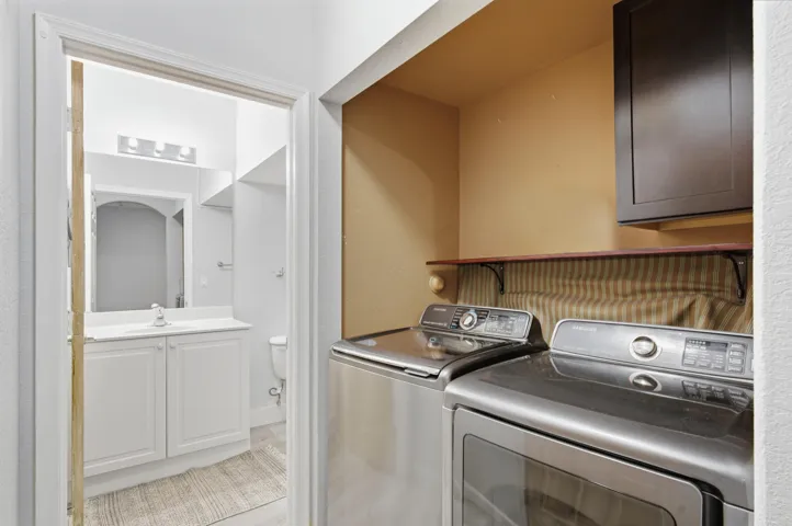 Built-in laundry appliances, overhead shelving, and wall-mounted cabinetry