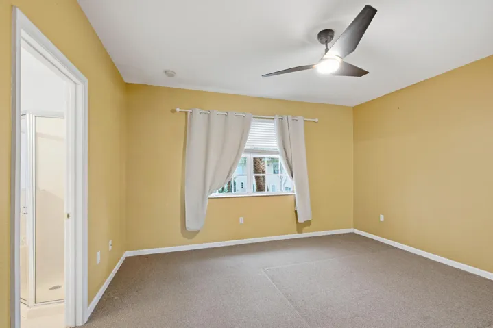 Recessed lighting, modern ceiling fan, carpet flooring, window with blinds, and an attached bathroom with a shower stall