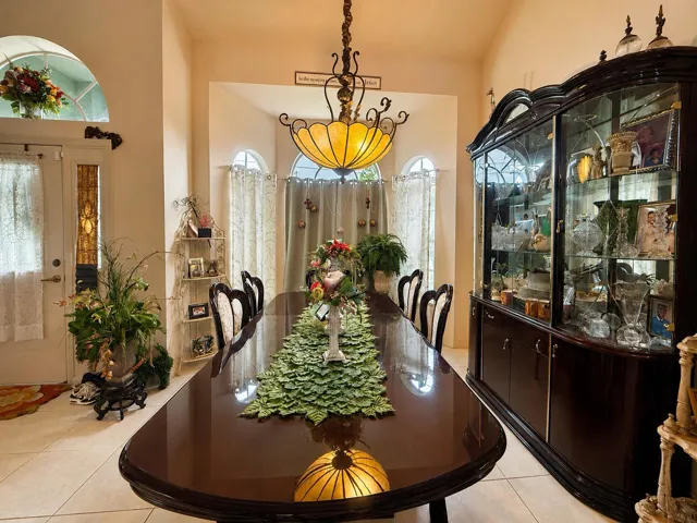 Arched transom window, recessed wall niche, tiled flooring, front entry with sidelight, and a decorative chandelier
