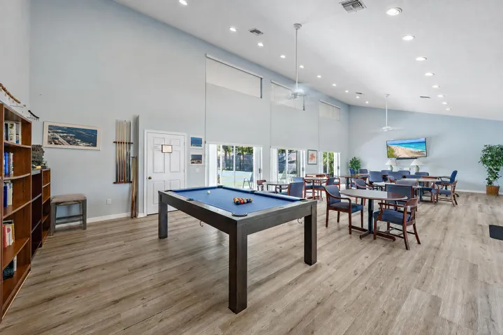 Community Room with Billiard Lounge Area. Floor to ceiling windows overlooking the tennis courts