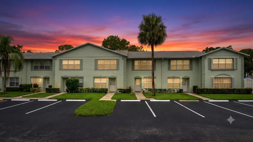 AI Enhanced Image Multi-unit residential structure with a pastel green exterior, accented by gray shutters and white trim