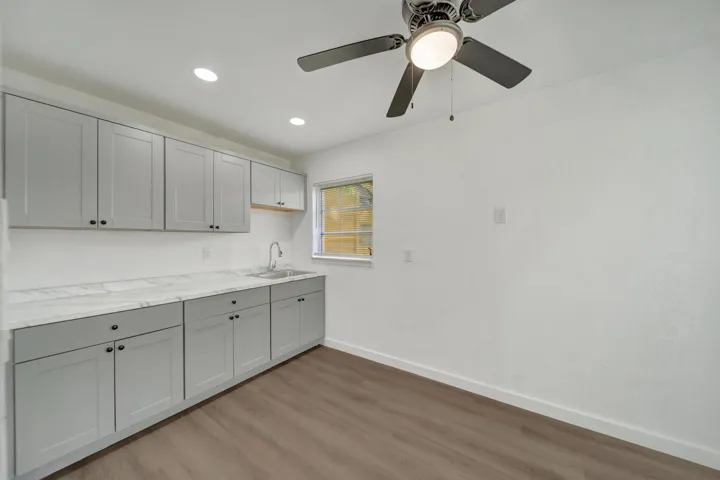 New Modern Efficient kitchen with Recessed lighting, wood-look flooring, tasteful light gray cabinetry, white countertops, and a modern ceiling fan.