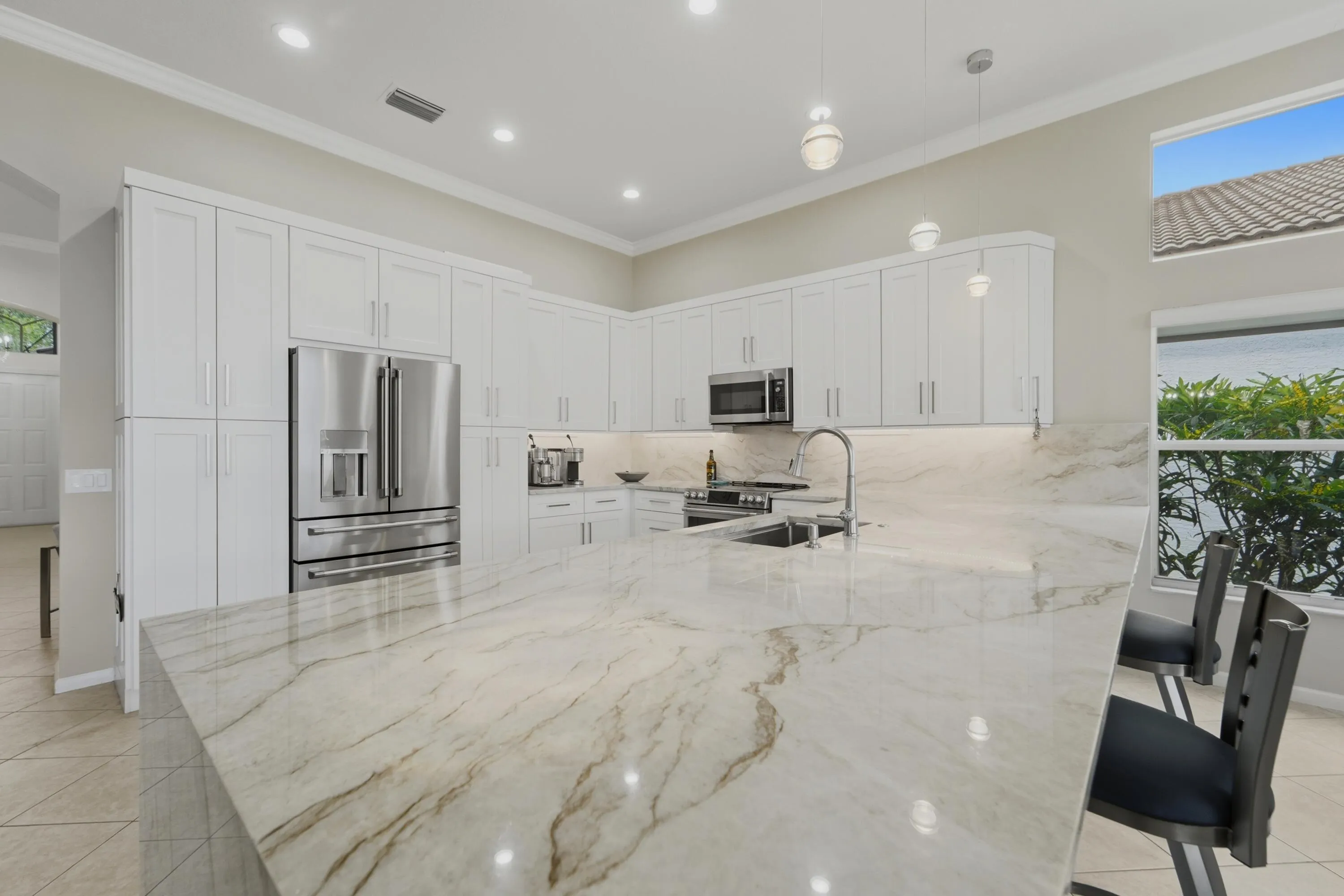 Renovated kitchen anchored by an oversized waterfall-edge island and open to the main living areas. Ideal for everyday living and entertaining. White shaker-style cabinetry, GE Cafe appliances and generous counter space complement the renovated kitchen. Extra wide peninsula with hidden outlet provides abundant workspace, extra storage and a natural gathering place at the heart of the home.