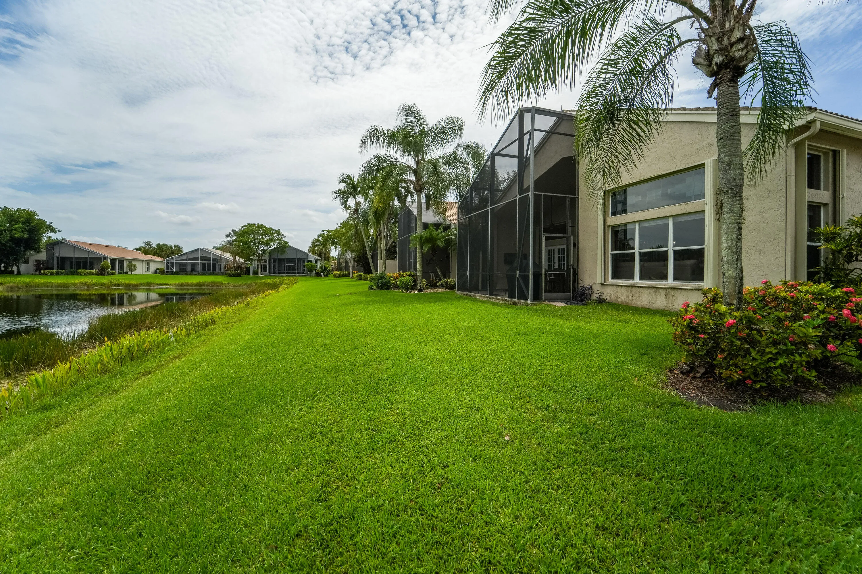 Rear elevation highlights the screened lanai, beautifully landscaped lawn and peaceful waterfront setting.