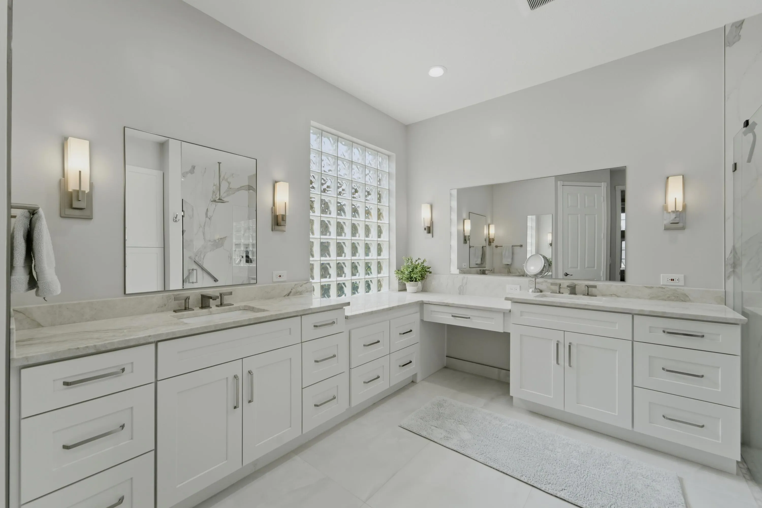 Generously sized primary bath offers dual vanities, abundant cabinetry and natural light from the glass-block window.