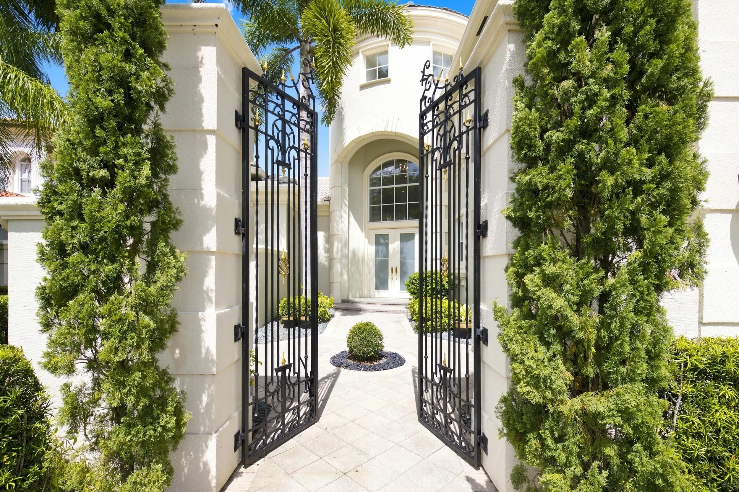Elegant gate entrance to manicured courtyard area with manicured landscape
