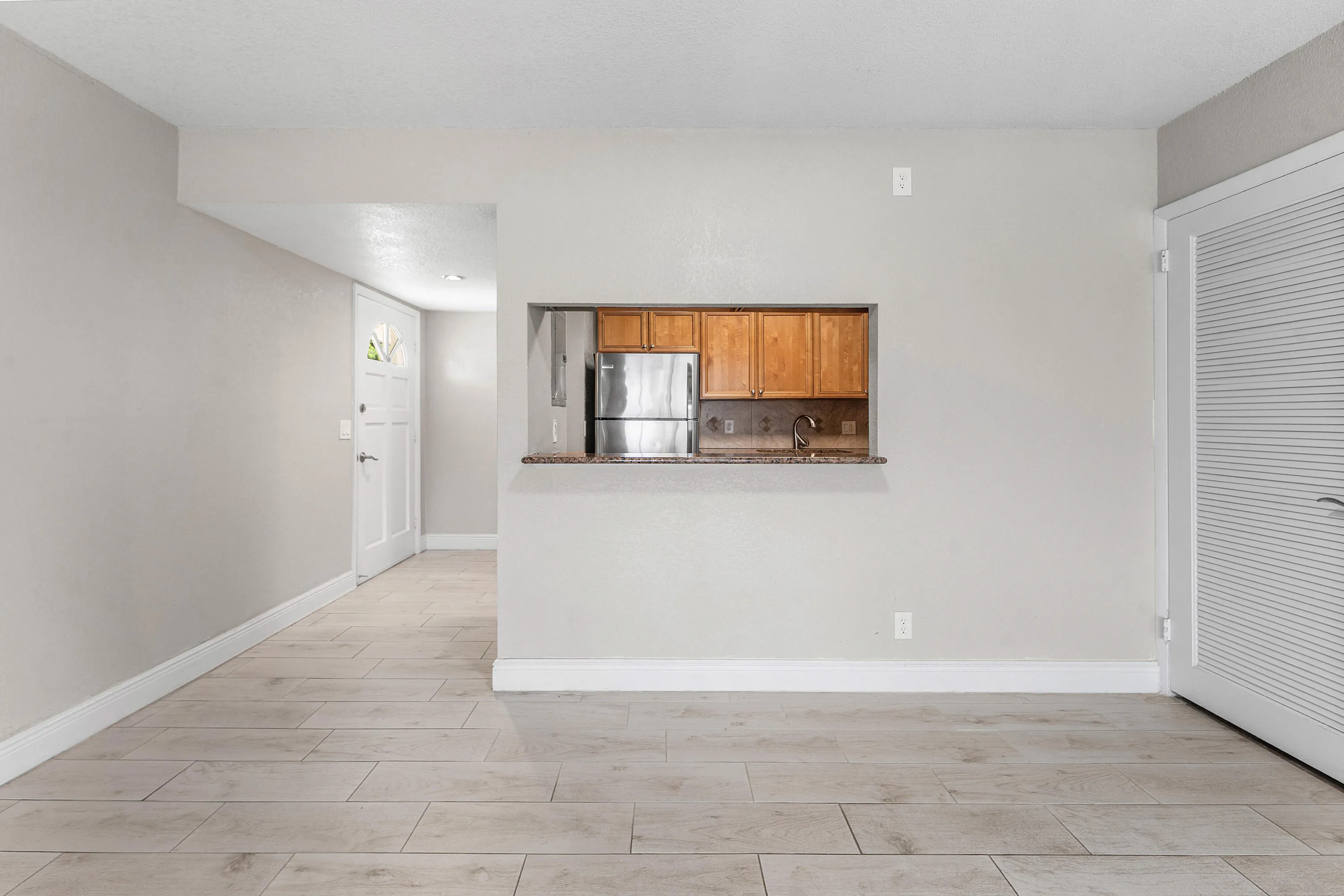 Light-toned plank flooring, neutral wall paint, and a pass-through window with a countertop