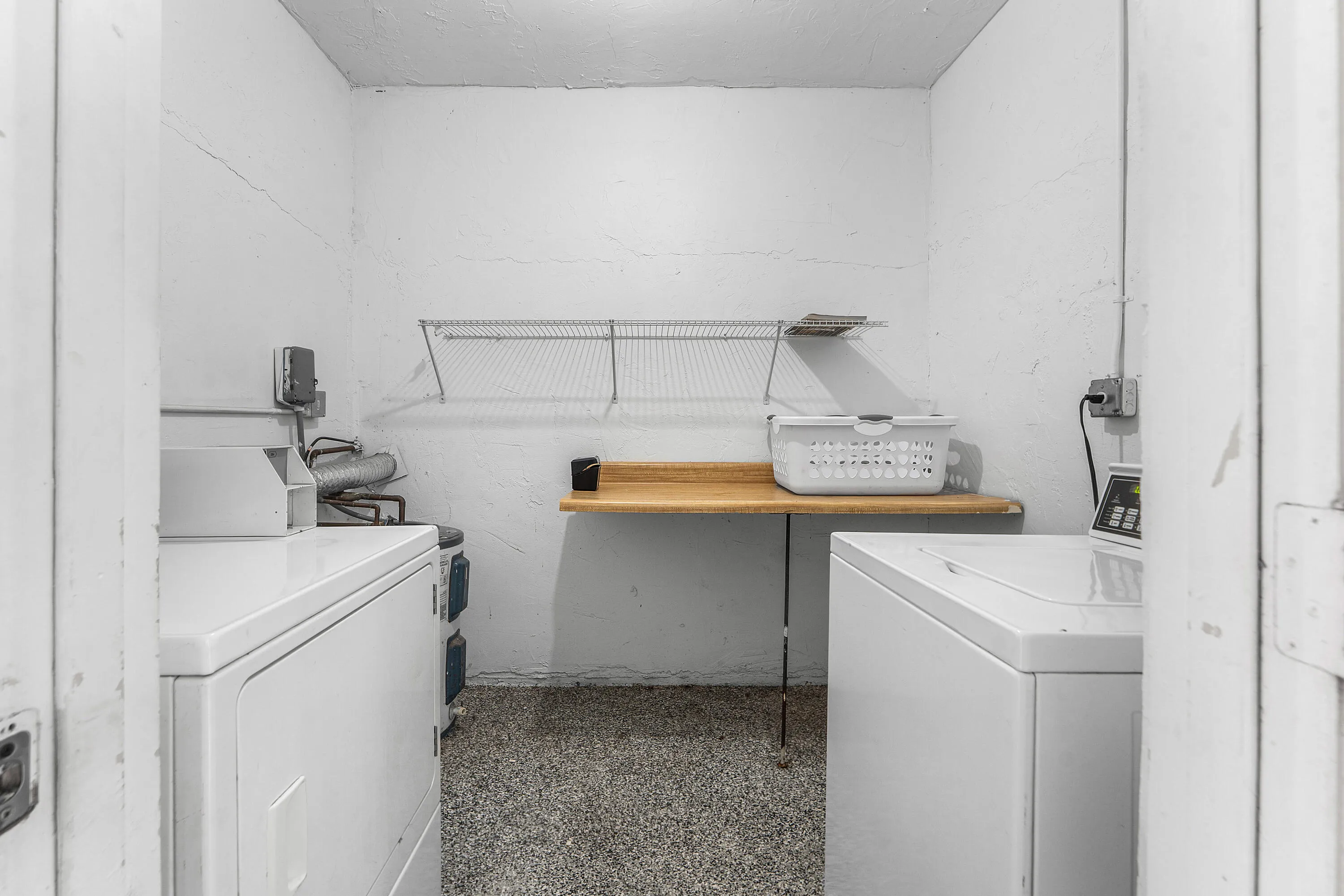 Laundry area with a wall-mounted wire shelf, built-in folding counter, and durable flooring