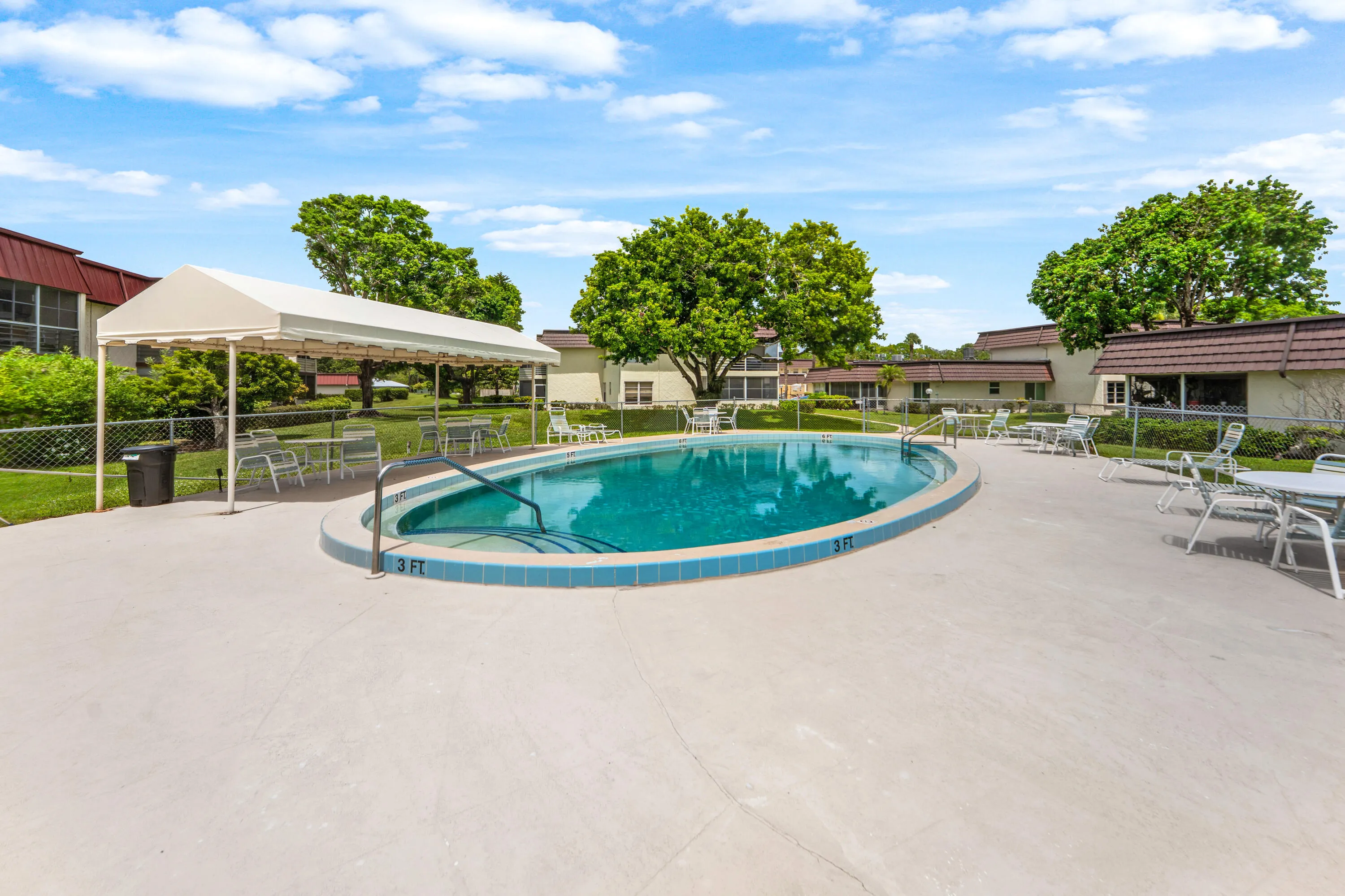 Oval-shaped pool with tile coping, concrete pool deck, and integrated pool steps