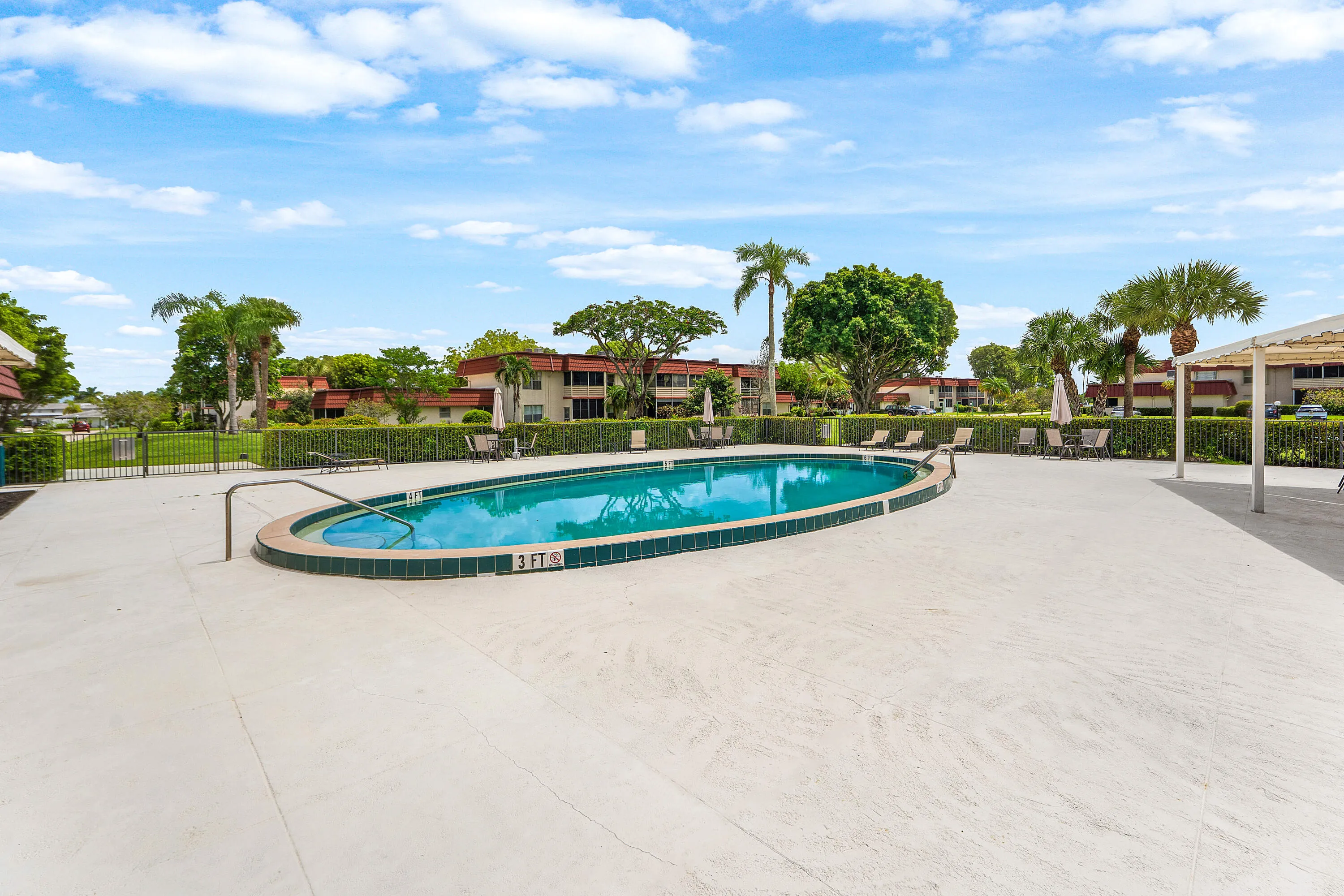 Oval-shaped swimming pool with tiled coping, surrounded by a concrete pool deck