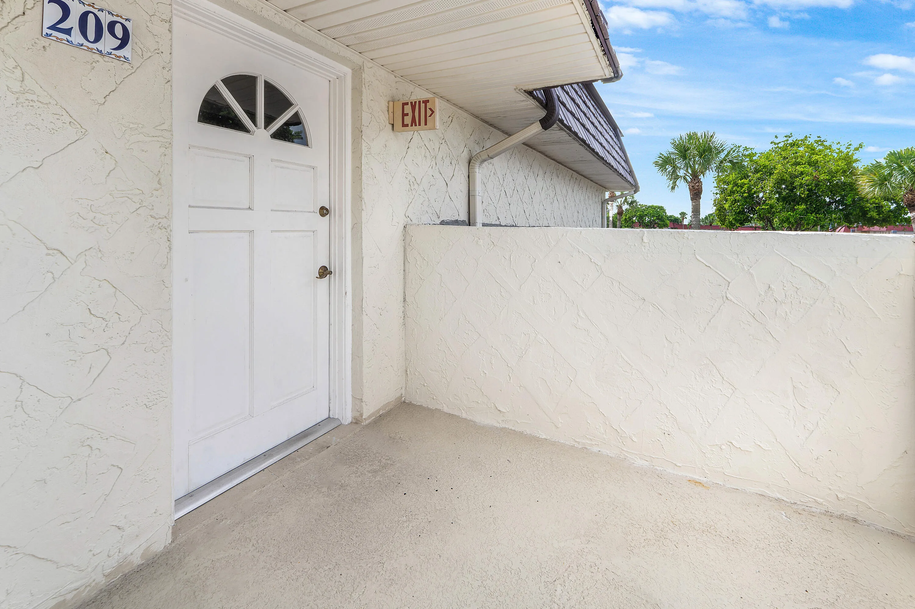 Private entry with textured stucco walls and a paneled door featuring an arched transom window