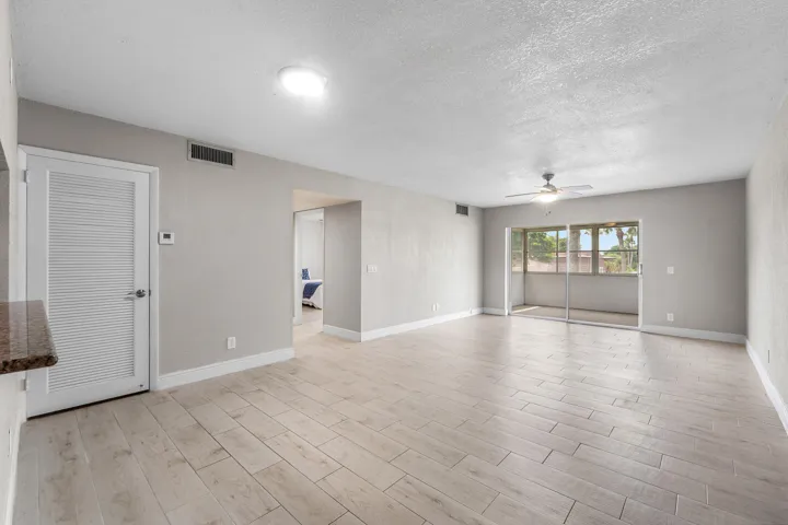 Spacious room with light-toned tile flooring, overhead lighting, and a ceiling fan