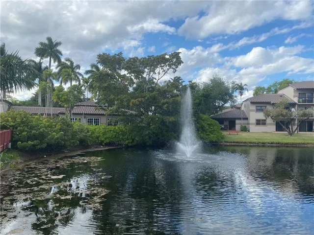 Pond with fountain feature, surrounded by mature trees and landscaping