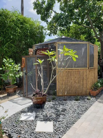 Hexagonal Aviary enclosure with double safety doors, and screened panels covered in natural bamboo.