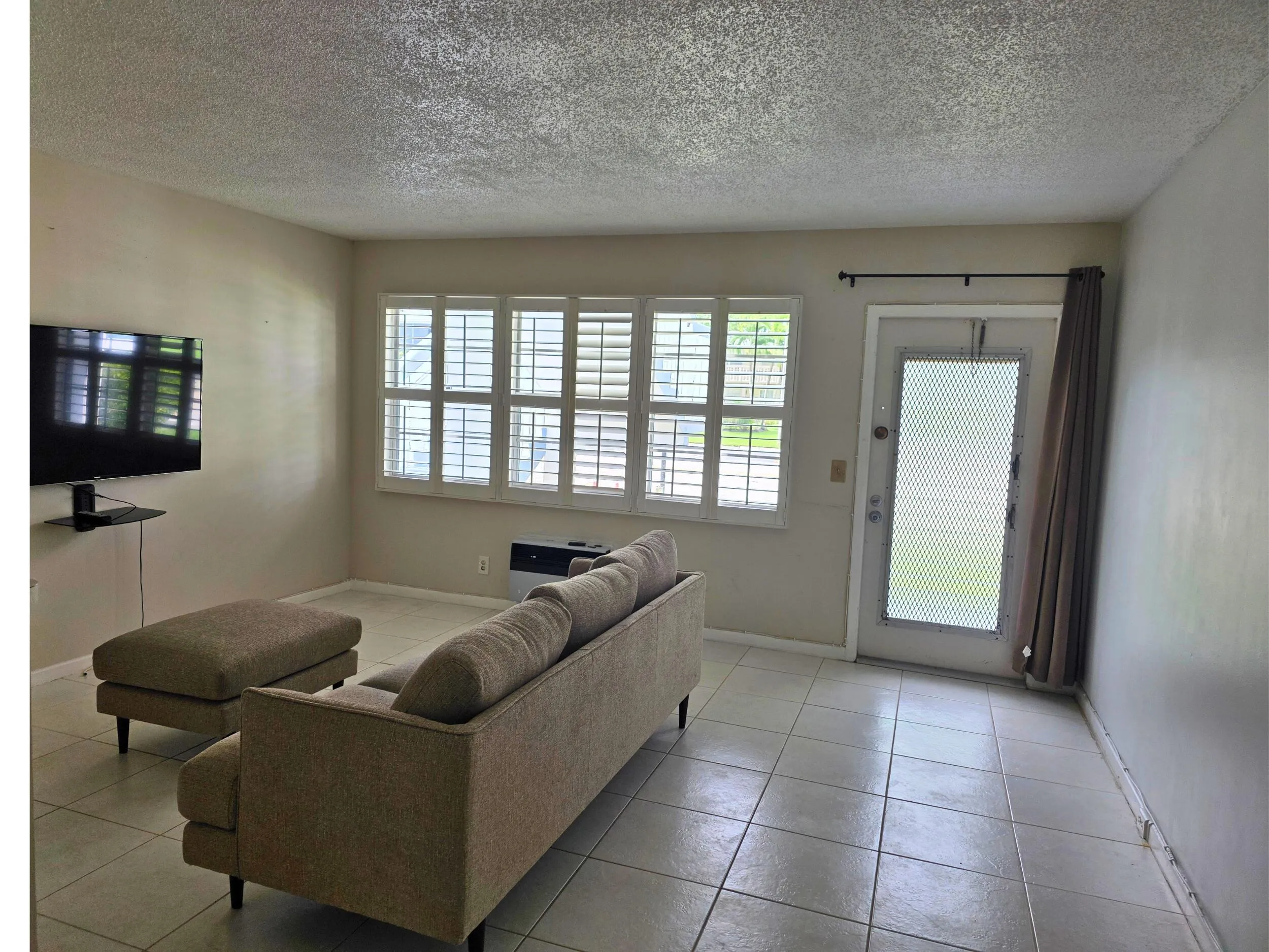 Tile flooring, white wall paint, shuttered windows, and a glass-paneled door