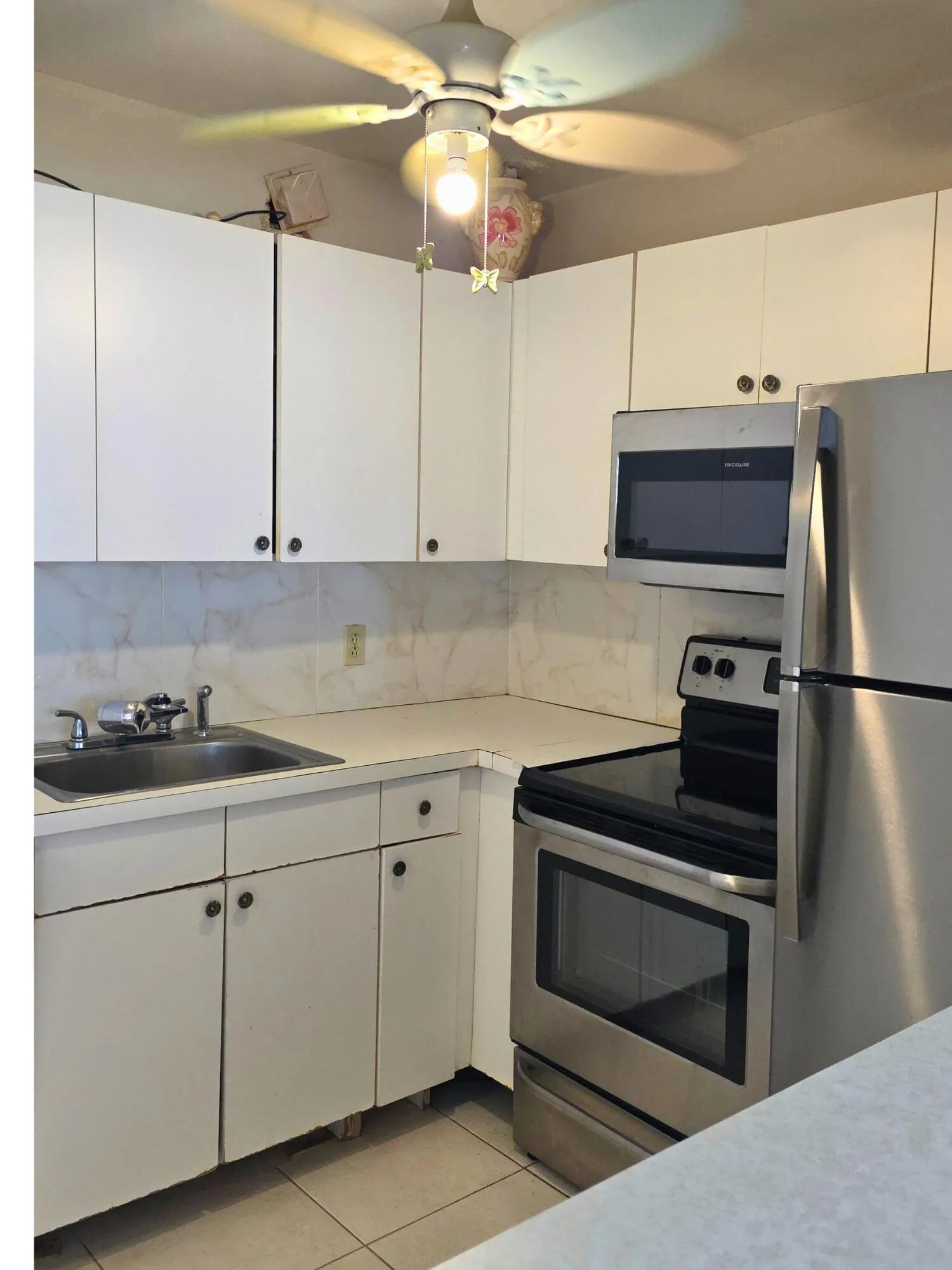 Kitchen featuring white cabinetry, light-toned countertops, and a tile backsplash