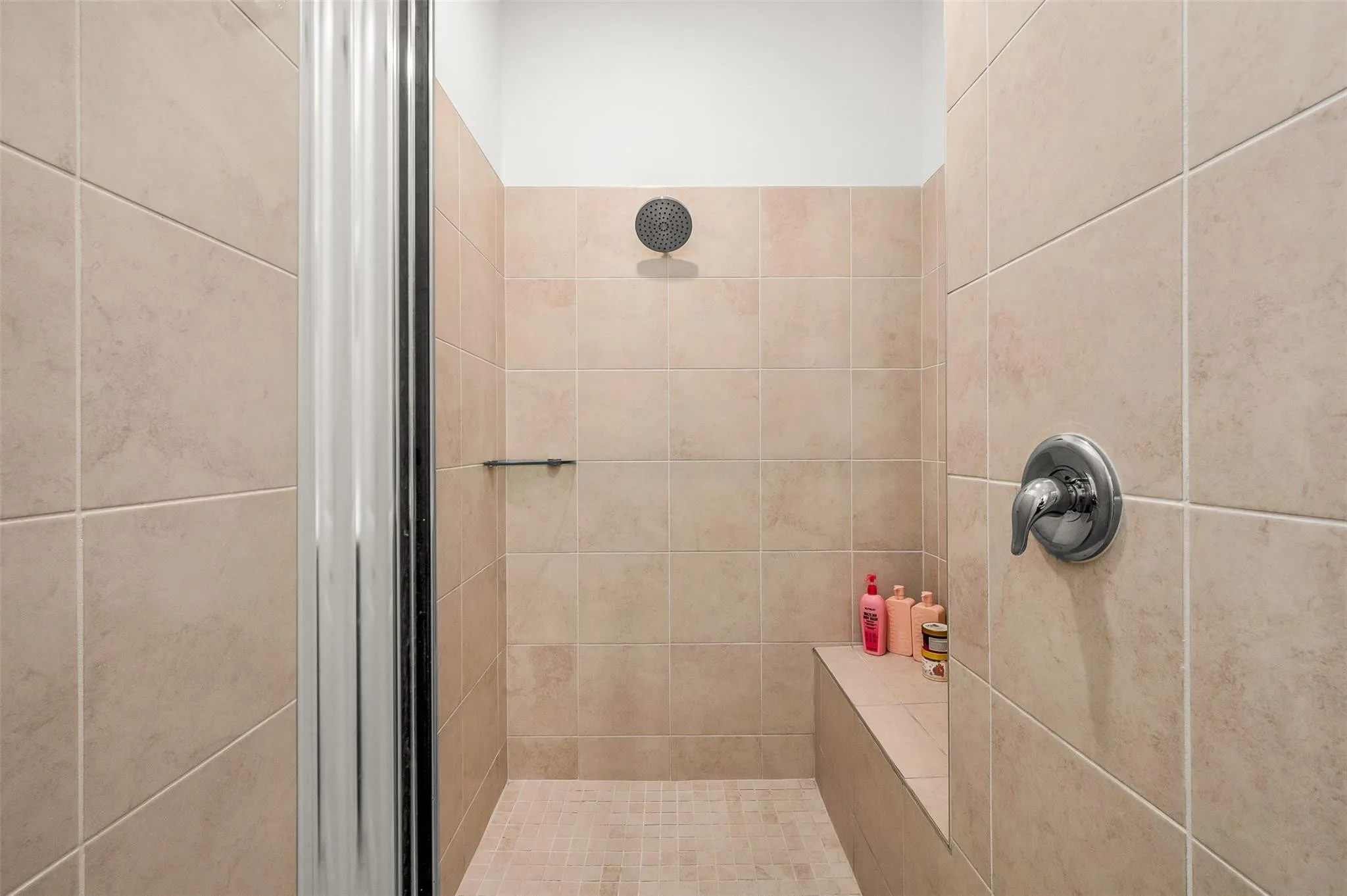 Tiled shower enclosure featuring a built-in bench