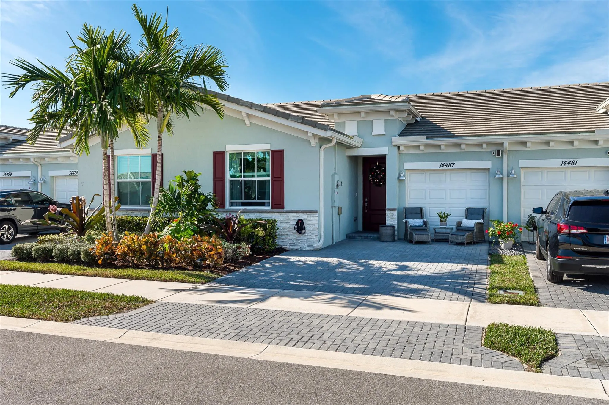 Tiled roofline, paver driveway, decorative red shutters, established landscaping, and a red front door