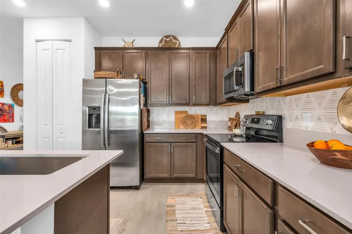 Kitchen featuring wood-finish cabinetry, stainless steel appliances, light-toned countertops