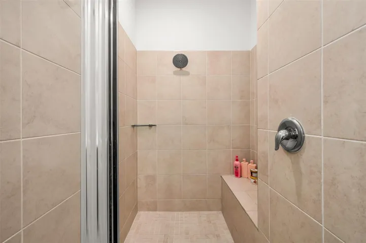 Tiled shower enclosure featuring a built-in bench