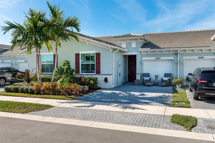 Tiled roofline, paver driveway, decorative red shutters, established landscaping, and a red front door