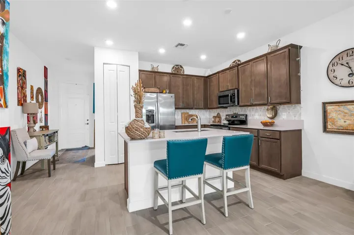 Kitchen featuring tile flooring, recessed lighting, a kitchen island with seating, wood cabinetry, and stainless steel appliances