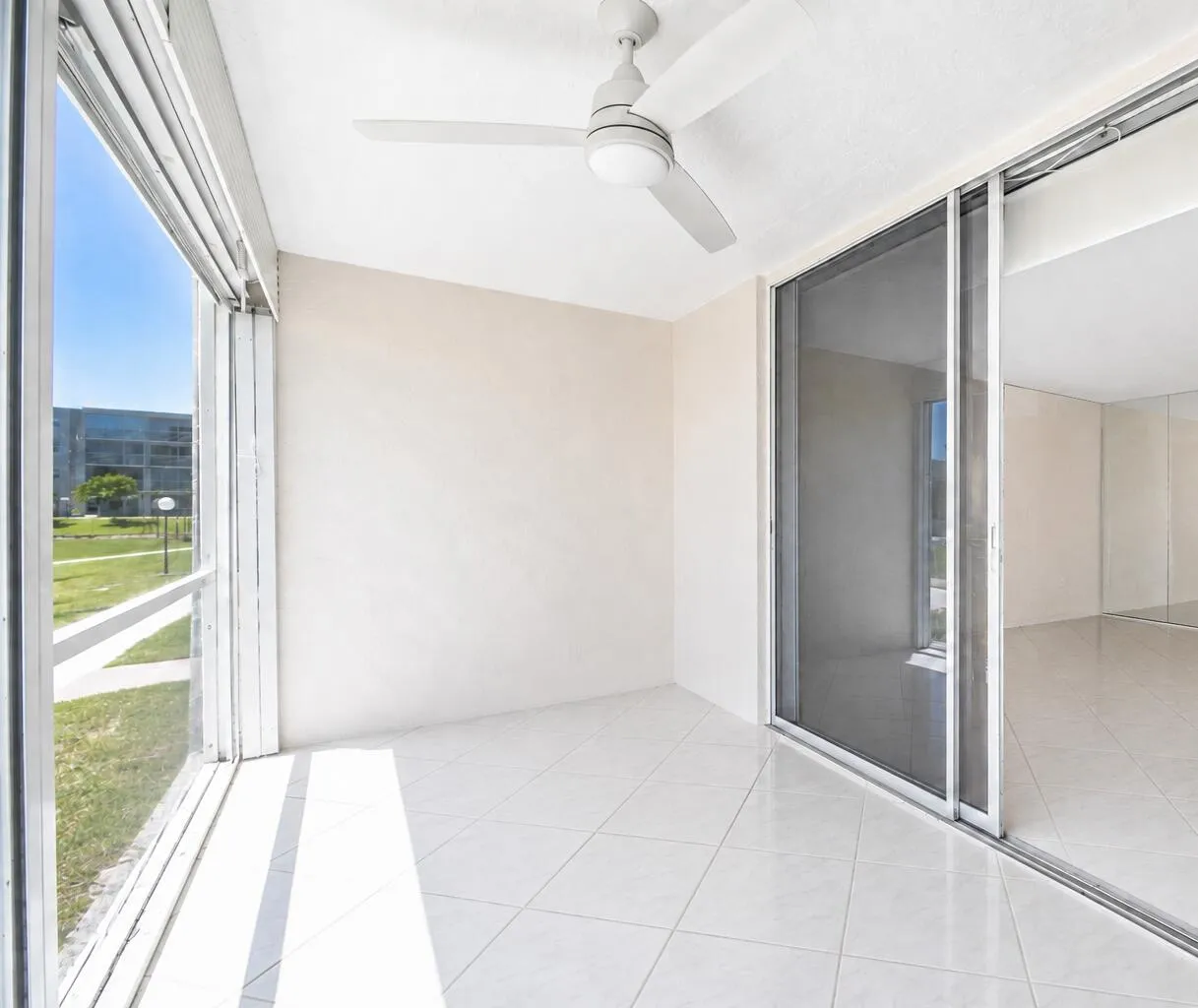 Screened balcony with tile flooring, ceiling fan, and sliding glass door