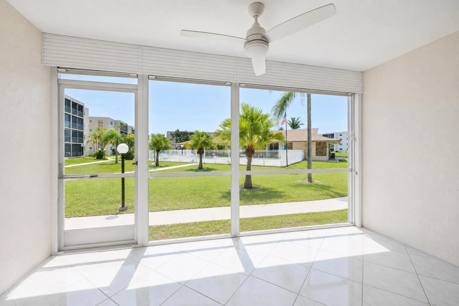 Bright, light-filled room showcasing expansive sliding glass doors that frame manicured landscaping and mature palm trees